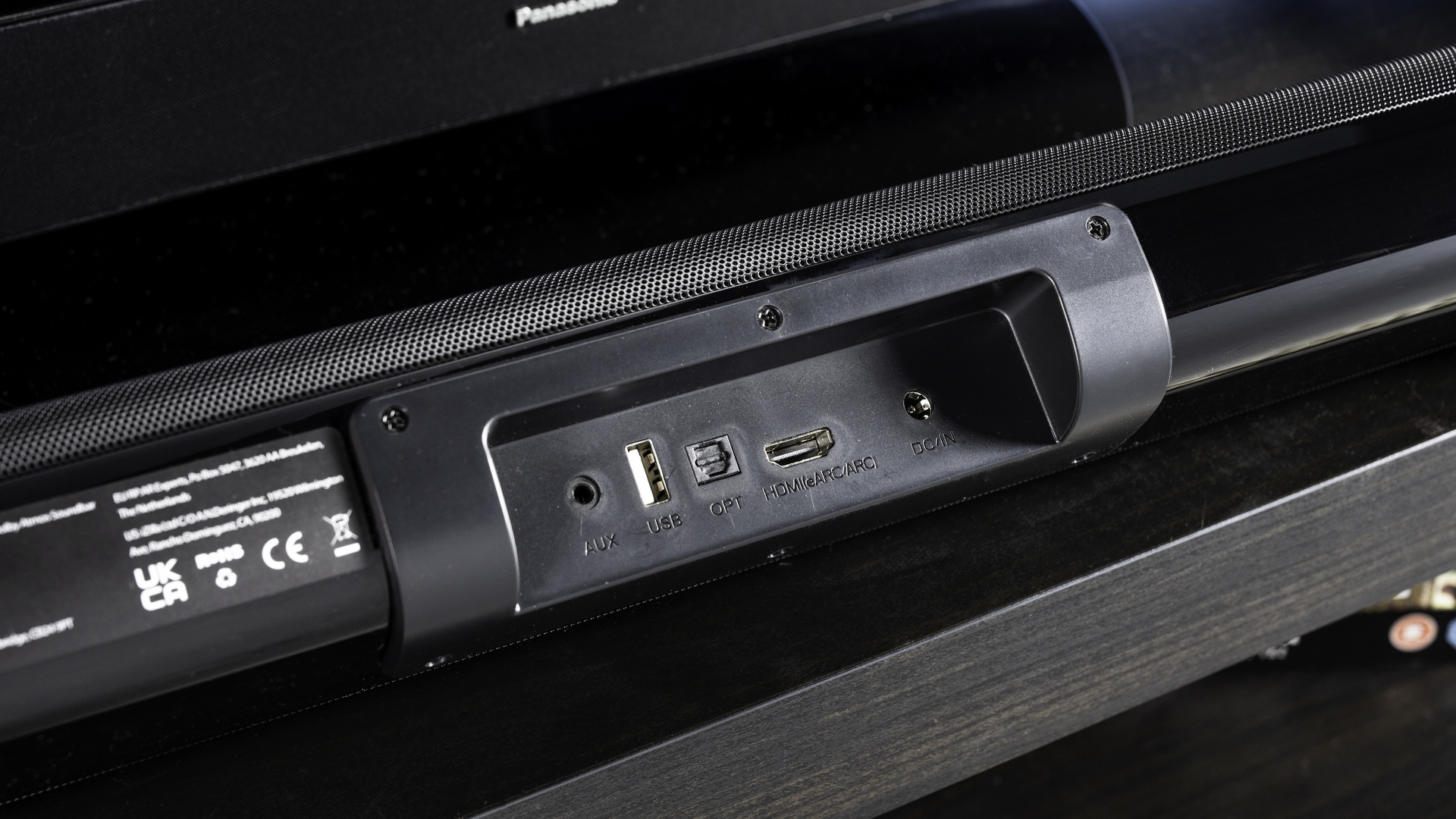 majority elias, a black soundbar with a silver majority logo, and a hdmi earc port and optical port, with a black remote, photographed on a black TV stand