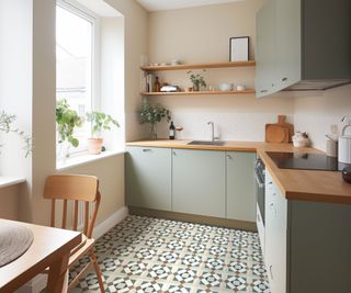 small green kitchen with patterned floor tiles and pink walls with open shelving