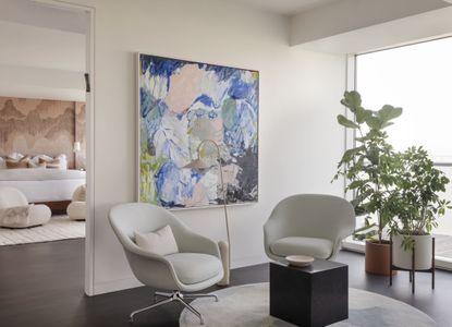 seating area by bedroom with white walls, chairs and colored art