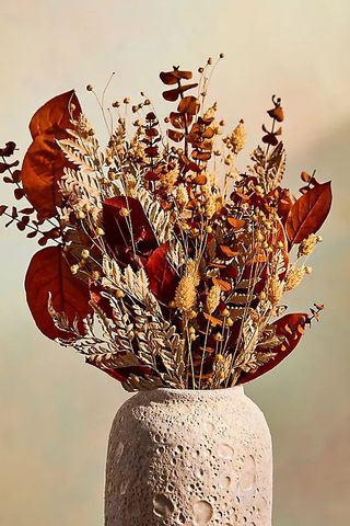 A dried bouquet of flowers in a stoneware vase