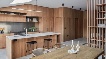 A modern style wood-panelled kitchen with the same material design carried throughout the space and a large island with a sleek grey worktop