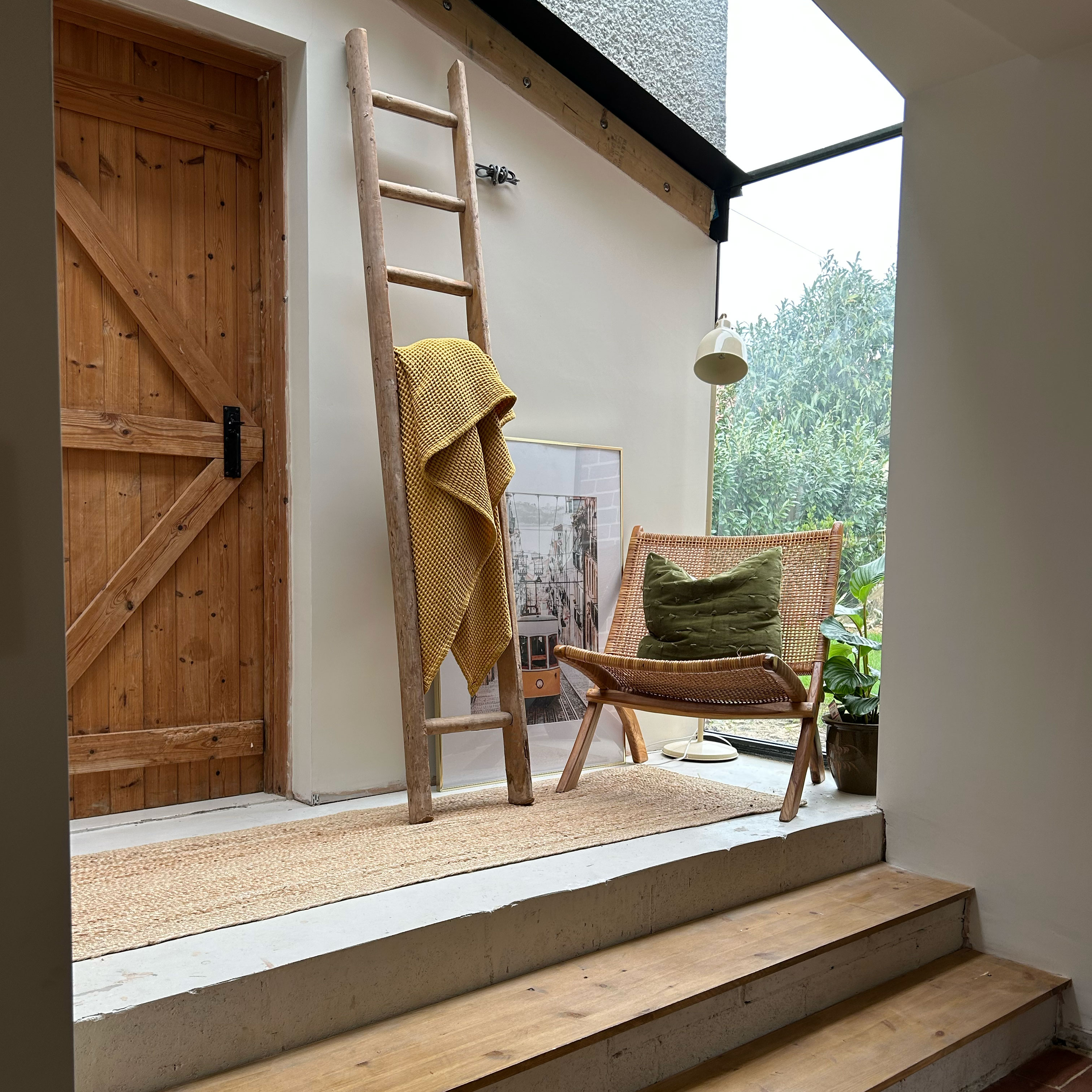 Corner in the hallway in the home with wooden steps, a ladder and a chair