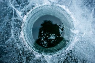 A shot from above of a hole drilled into an ice lake