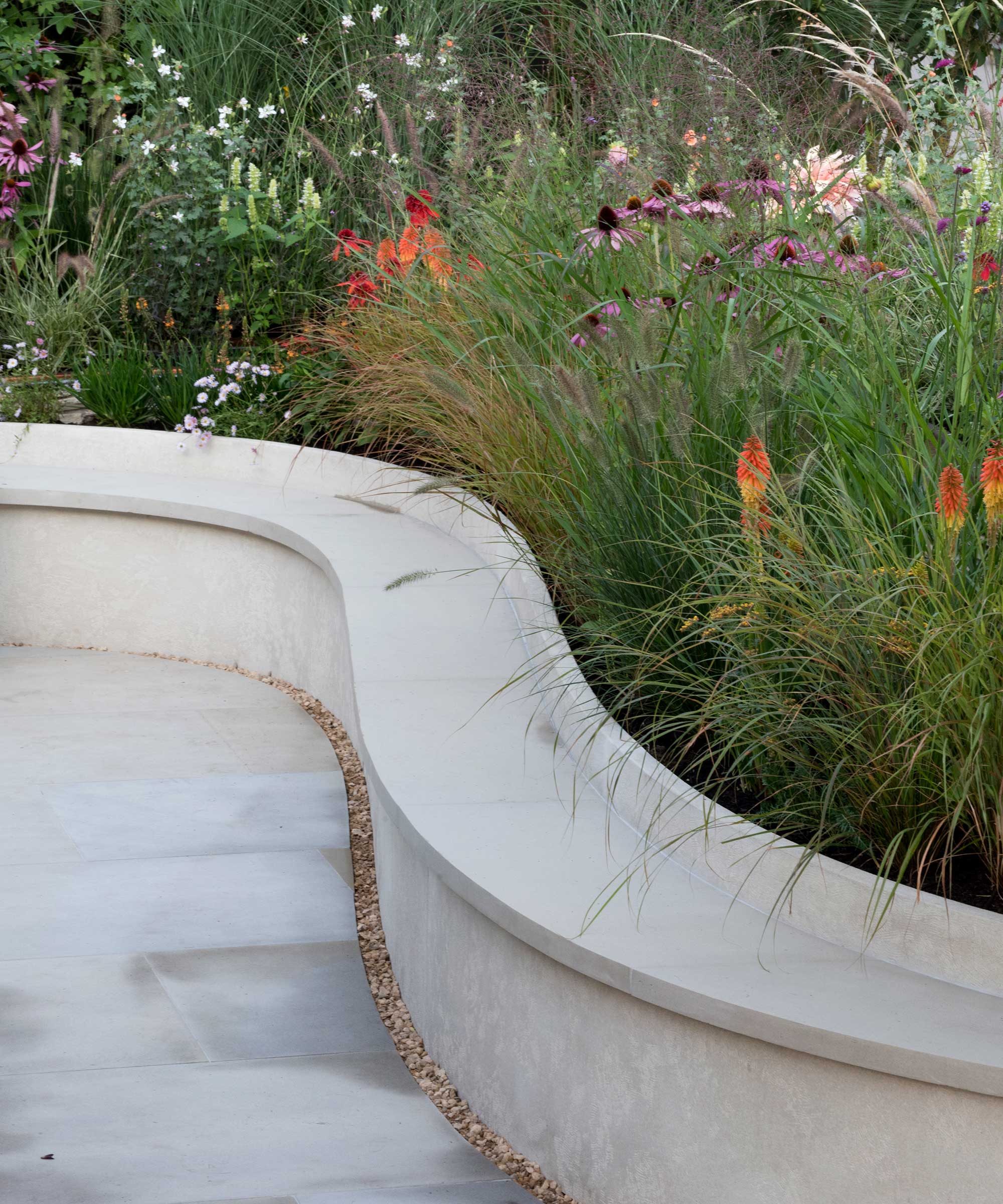 pebbles alongside paving and raised beds with flowers at Finding Our Way – An NHS Tribute Garden by Naomi Ferrett-Cohen at Chelsea flower show 2021