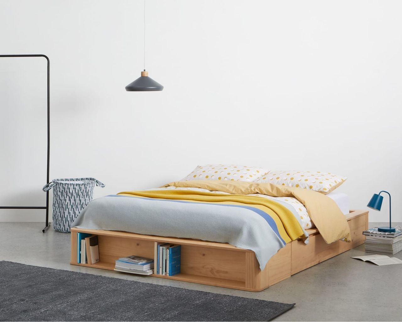 MADE.com Kano Double Platform Bed with Storage Drawers on floor in bedroom with blue and yellow bedding