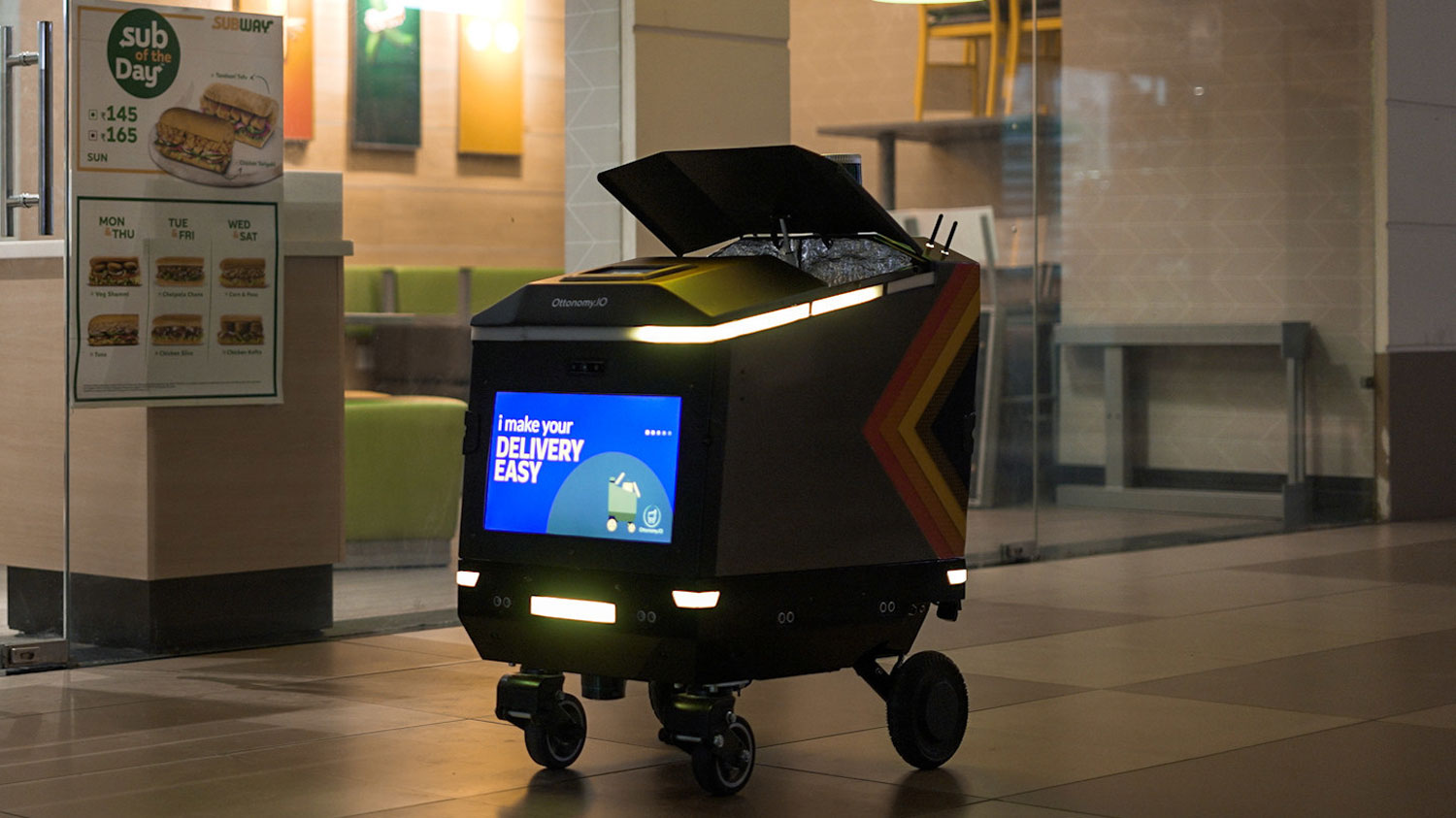 An Ottonomy delivery robot, which looks like a self-propelled shopping cart, in an indoor mall.