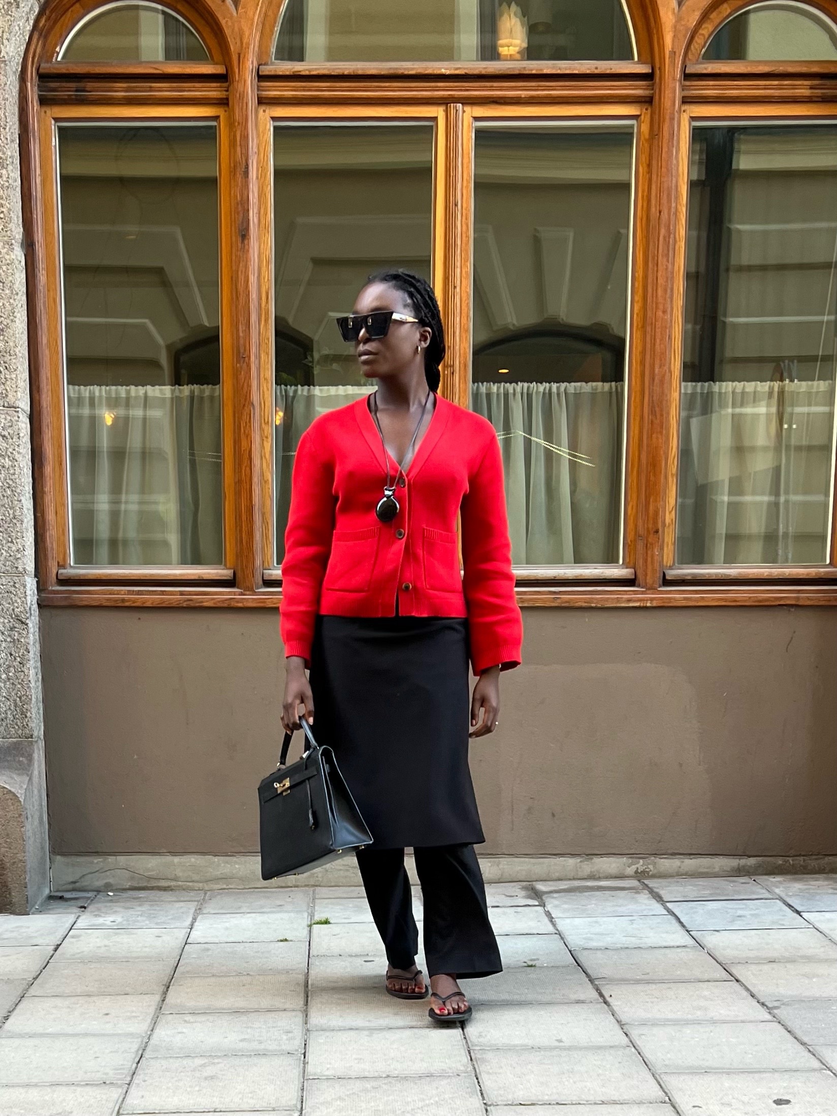 Influencer Chrystelle Eriksberger wearing a cardigan, overlay trousers and top-handle bag.