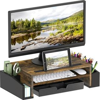 A dark brown wooden computer monitor stand with black metal storage on either side for stationery. 