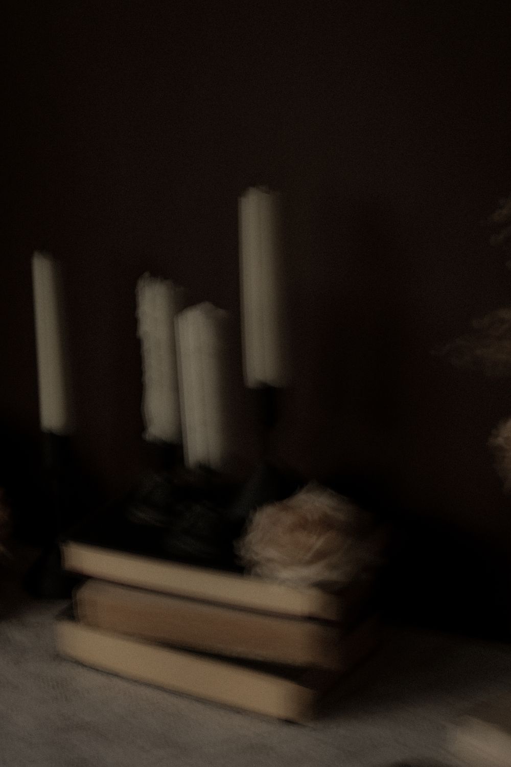 A stack of crime novels in soft focus on a wooden table under moody lighting.