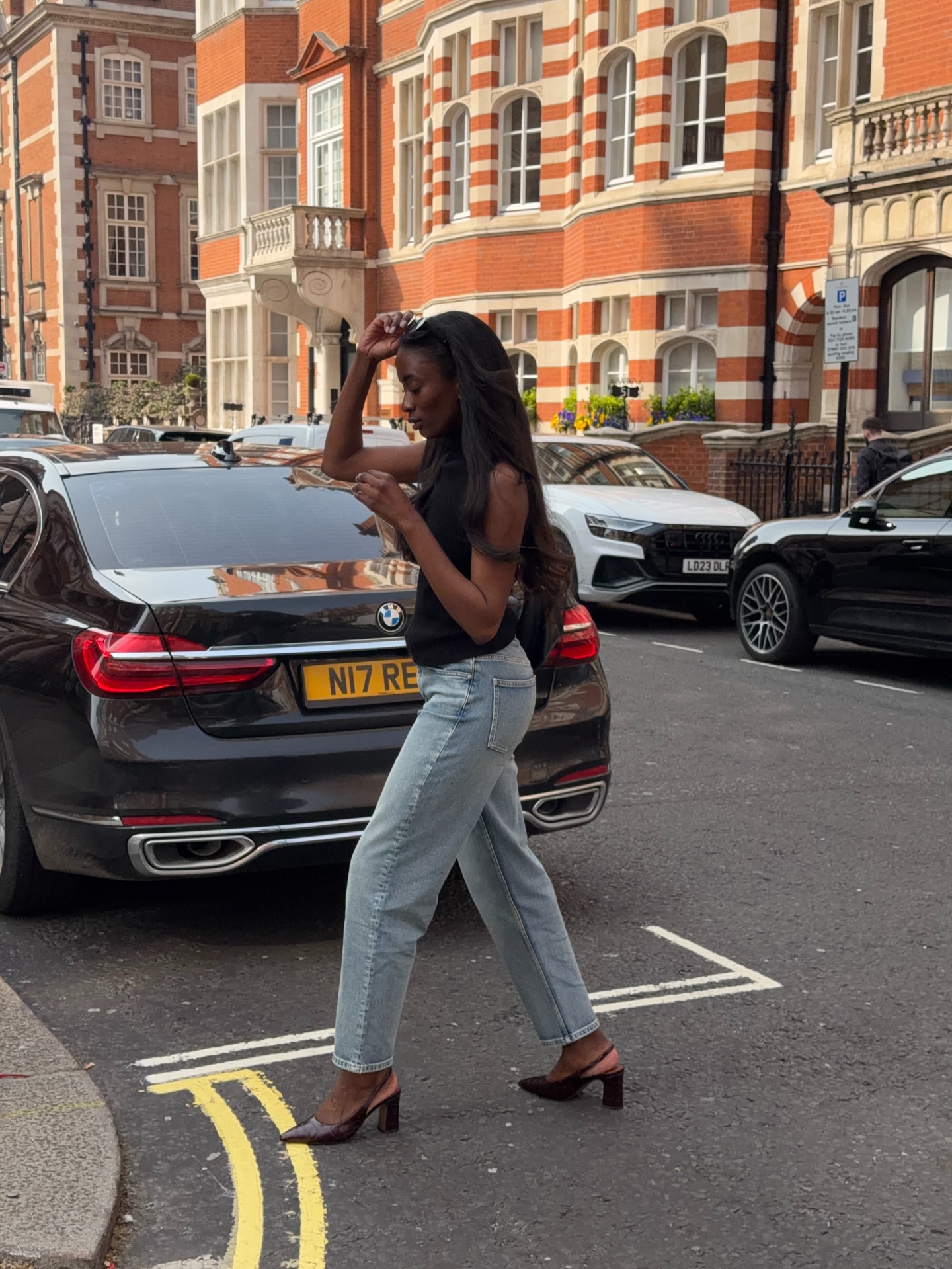 Liv wears a black top with blue jeans and slingback heels