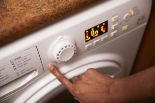 A person pressing a button on a washing machine