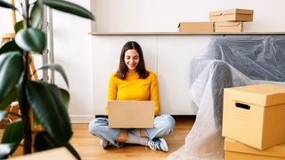 Student using a laptop while moving into new apartment