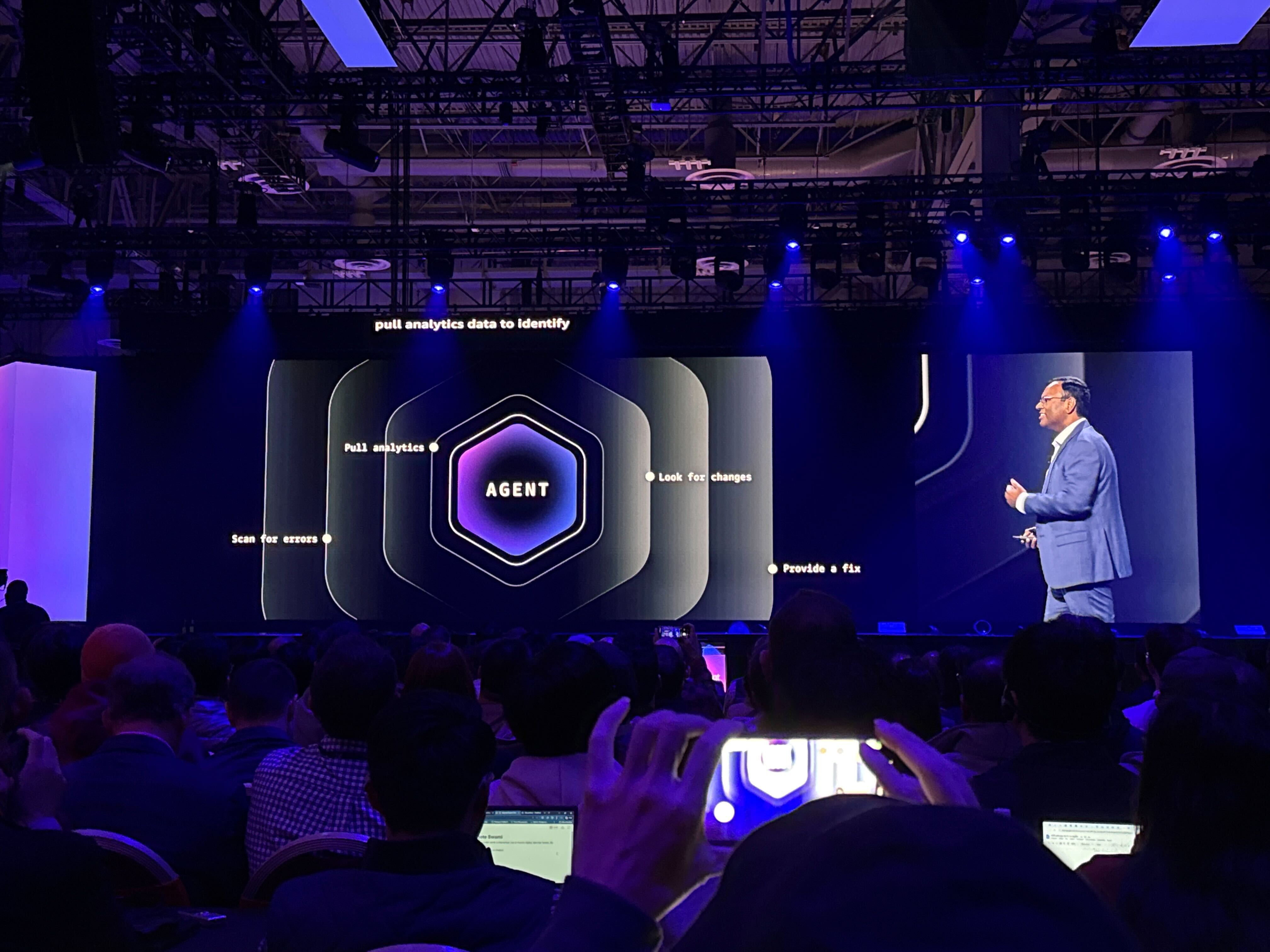 Swami Sivasubramanian pictured on stage at AWS re:Invent discussing the differences between AI chatbots and agentic AI.