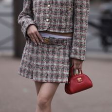 Woman wearing a Miu Miu mini-skirt suit and Miu Miu micro bag