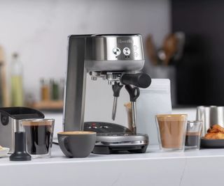 The Breville Bambino on a countertop with a range of different coffees sat in cups and glasses around it