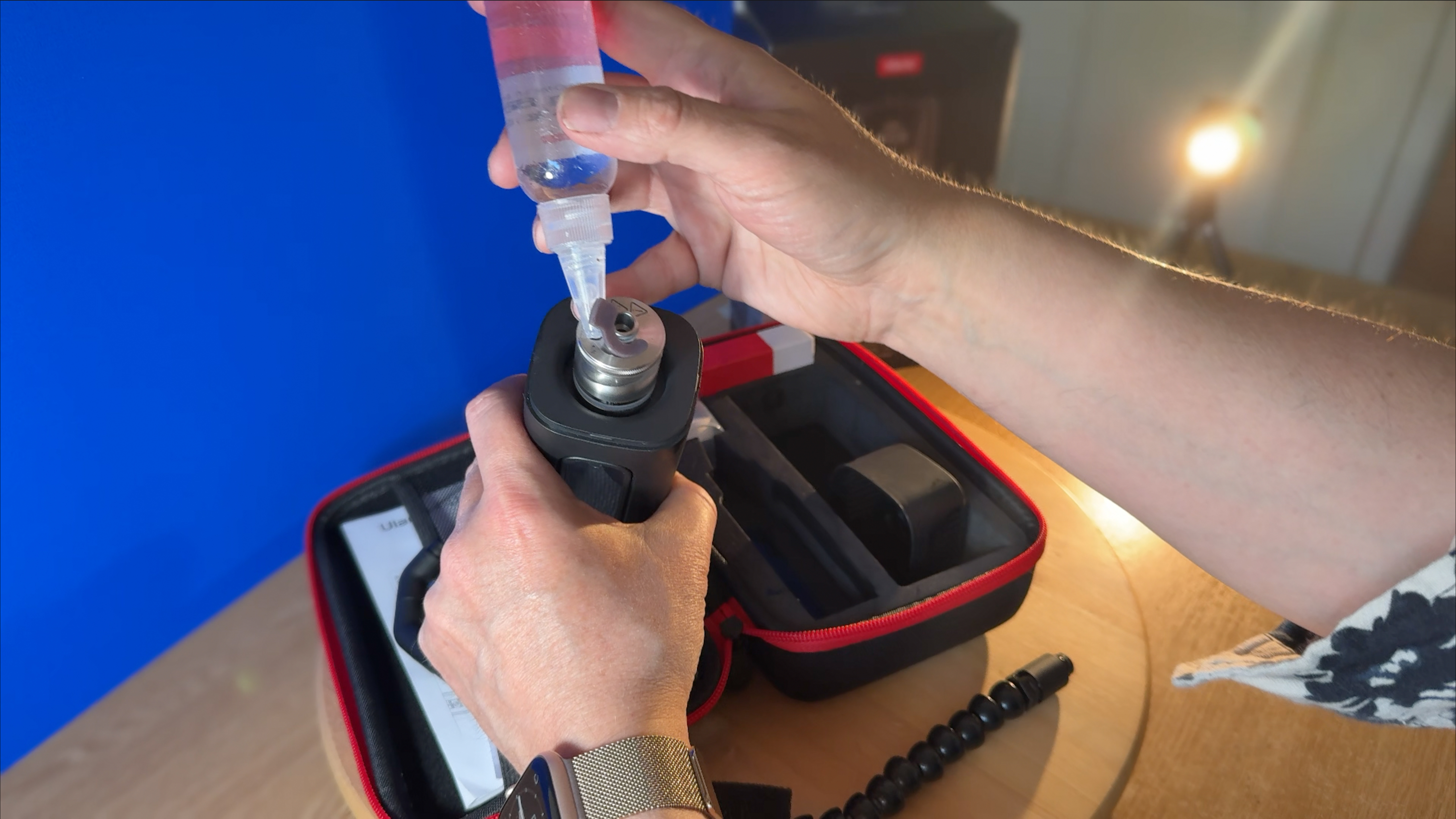 A hand pours liquid fuel from a plastic bottle into the fuel tank of the Ulanzi fog machine