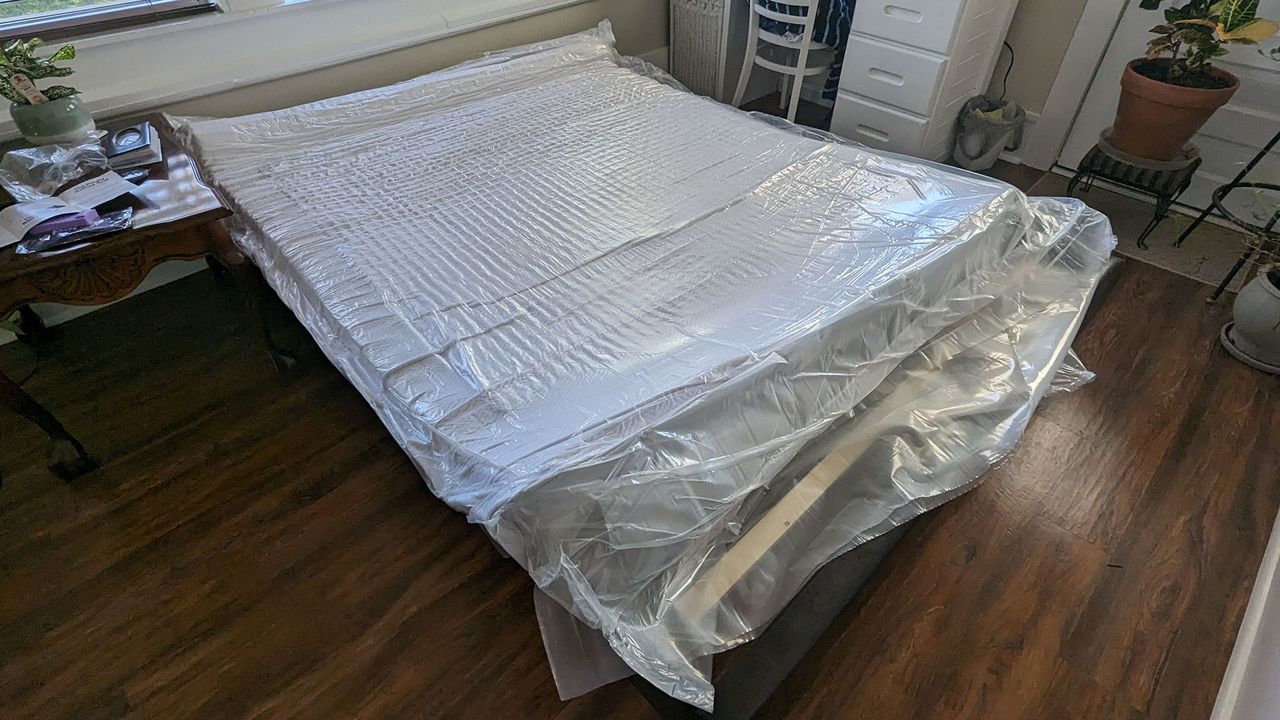 Purple NewDay mattress unrolled on the bed frame