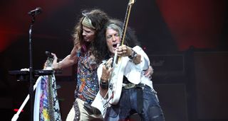 Joe Perry solos on a white Strat with Aerosmith frontman Steven Tyler (left) by his side