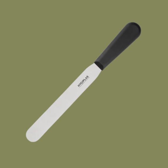 A stainless steel palette knife with a black, sturdy handle sits against a forest green background.