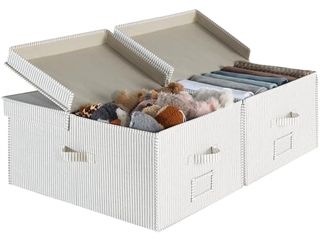 Two large storage boxes with flip lids filled with stuffed toys and folded clothes. 