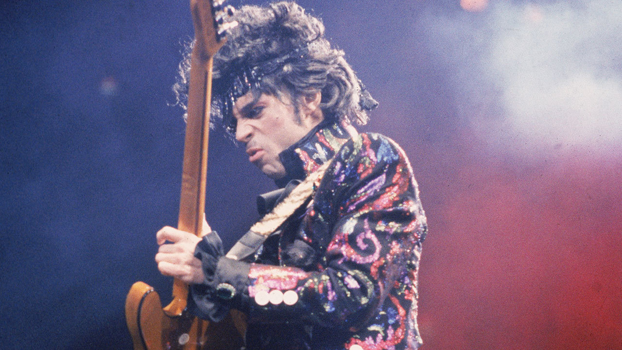 A photo of Prince playing guitar on stage