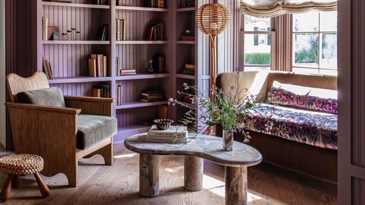 Wooden, purple shelves in a living room with a wooden armchair and kidney shaped stone coffee table