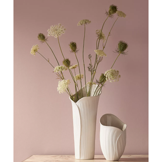 white stoneware vase in an elongated flower bud shape with flowers inside
