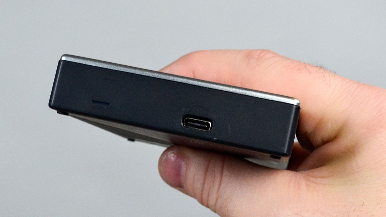 A masculine hand holding a WD My Passport Ultra for Mac