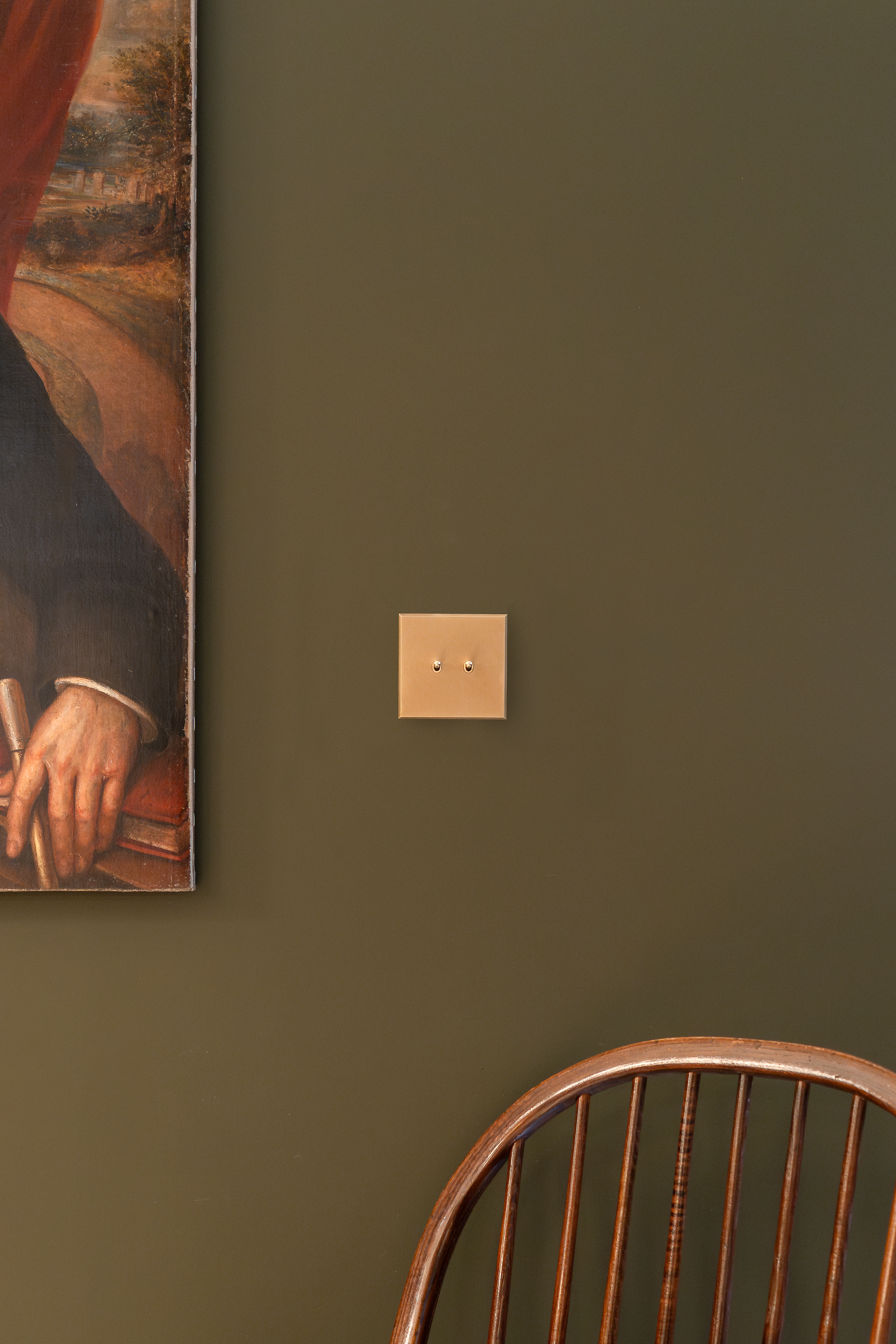 Soho Lighting Co. kinetic switch on a green wall next to a painting