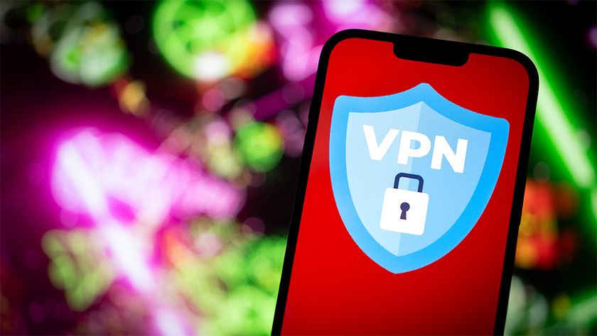Smartphone displaying blue VPN shield logo with a padlock. There is a green and pink blurred technological background