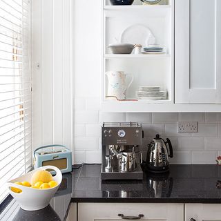 kitchen with white walls marble worktop and fruit ball