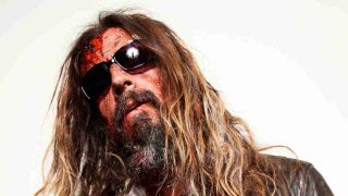 Rob Zombie posing for a photography wearing sunglasses with blood on his face