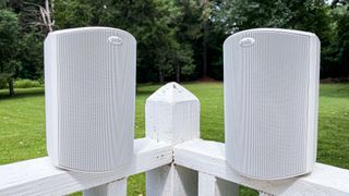 Hero image for best outdoor speakers showing Polk Atrium 4 speakers placed outside on a white fence