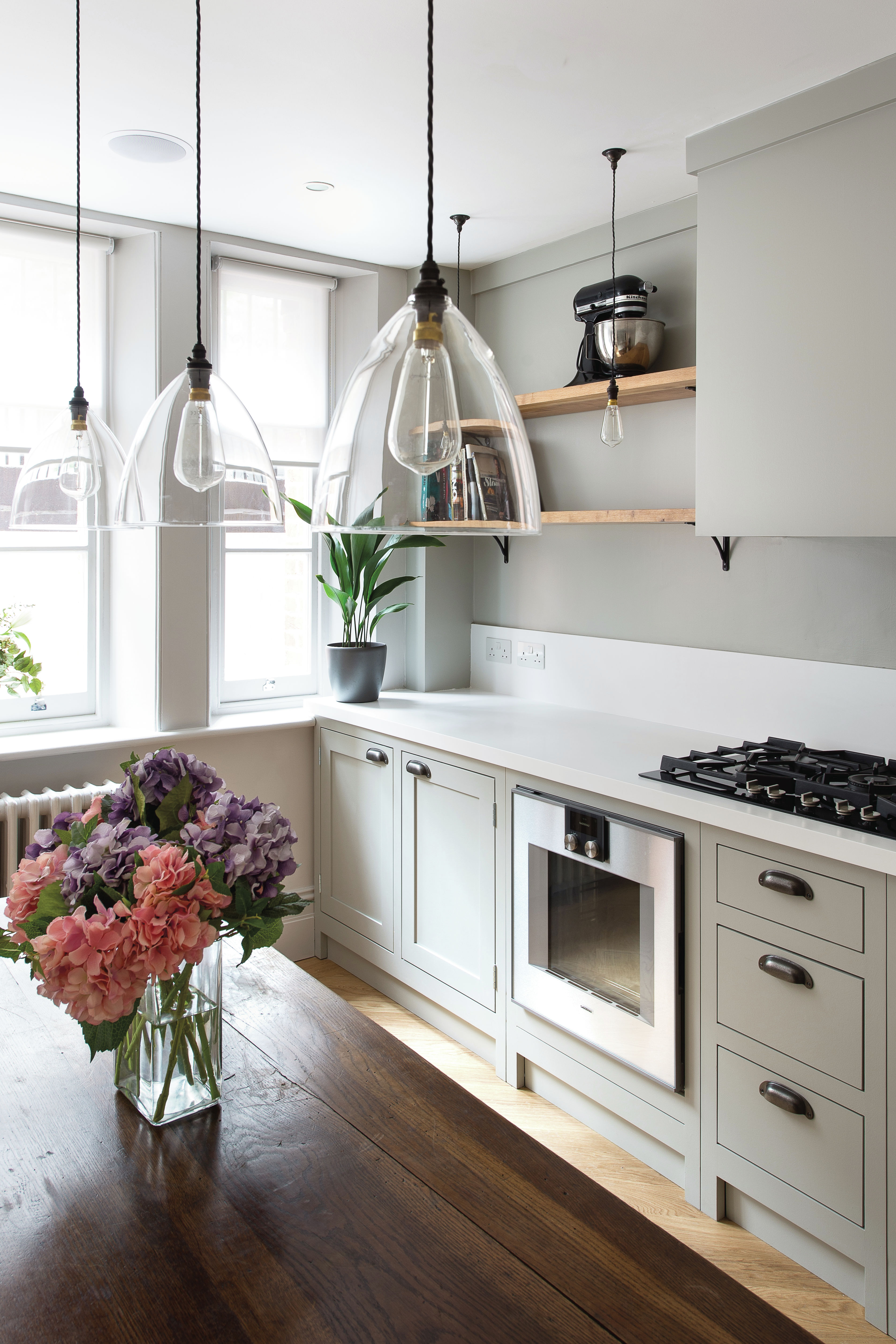 A grey kitchen by Fritz Fryer with trio of glass pendant ceiling lights over island