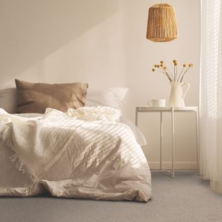 carpet colour trends for 2023, neutral bedroom scheme with neutral carpet, white bedding, taupe pillows, rattan pendant light, white metal side table
