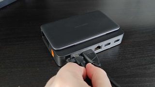 Hand inserting USB-C cable into Baseus 6-in-1 Steam Deck dock