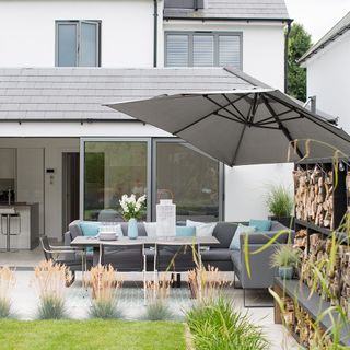 sloping roof house with grey sofa table at balcony and grass lawn