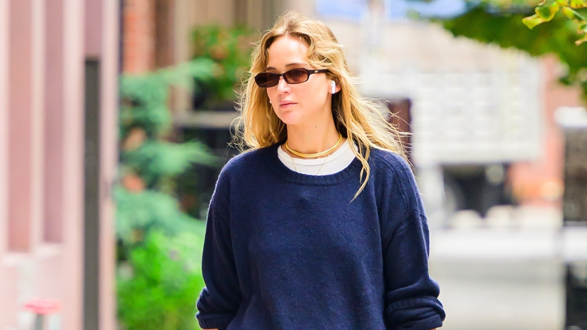 Jennifer Lawrence wearing a navy sweater, red track pants, studded bag, and flat mules in NYC