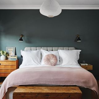 Master bedroom with dark green walls and double bed with dusty pink throw.