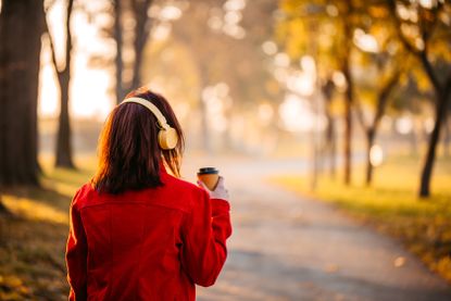 Woman walking in park listening to music.