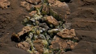 A photo showing a pile of rocks with yellow crystals inside