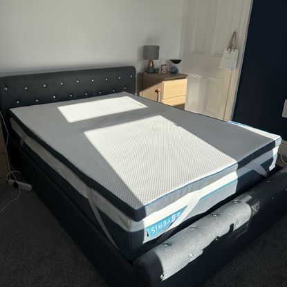 The Simba Hybrid mattress topper on a grey upholsterd bed in white bedroom