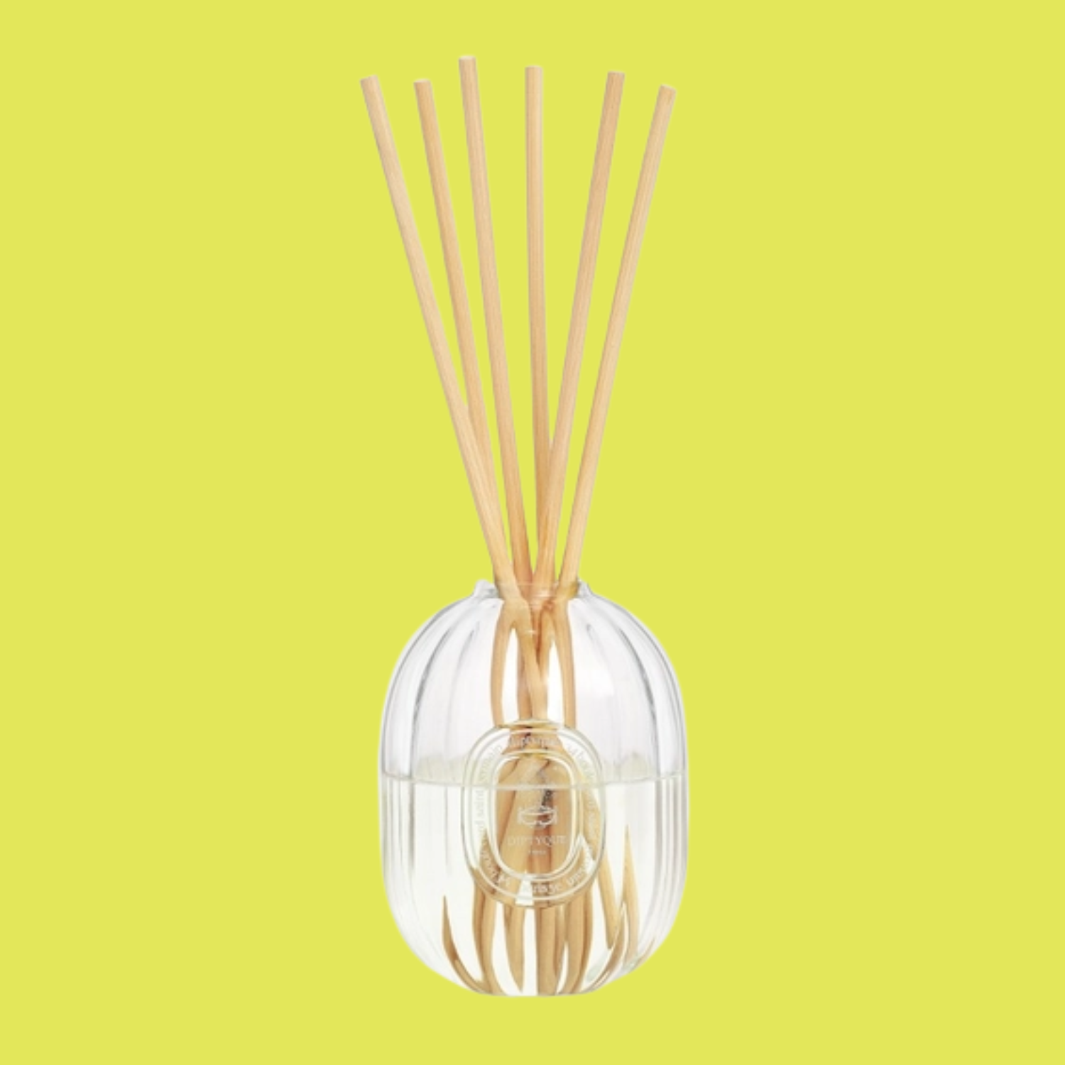 A glass reed diffuser with wood reeds
