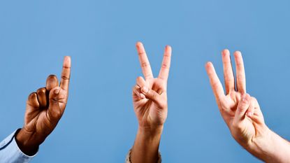 Three hands hold up one finger, two fingers and three fingers against a blue background.