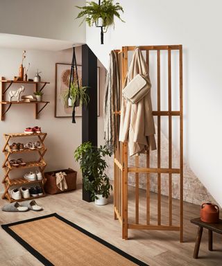 A small entryway with a shoe rack, wooden partition, and wall shelves
