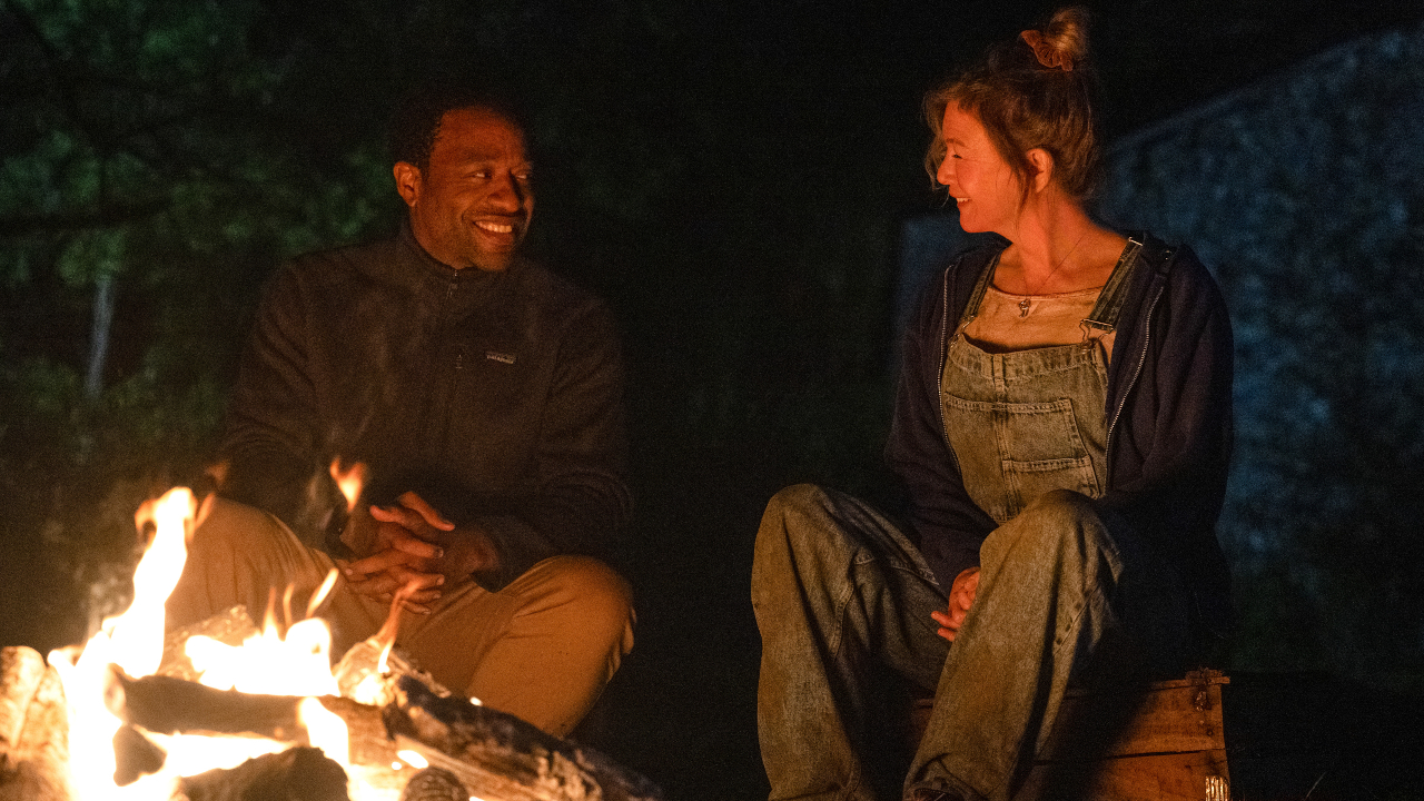 Chiwetel Ejiofor sits and smiles with Renee Zellweger around a campfire in Bridget Jones: Mad About The Boy.