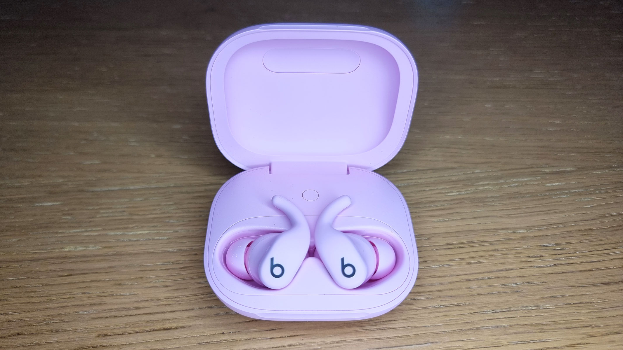 A close-up picture of the Beats Powerbeats Fit earbuds sitting in an open charging case