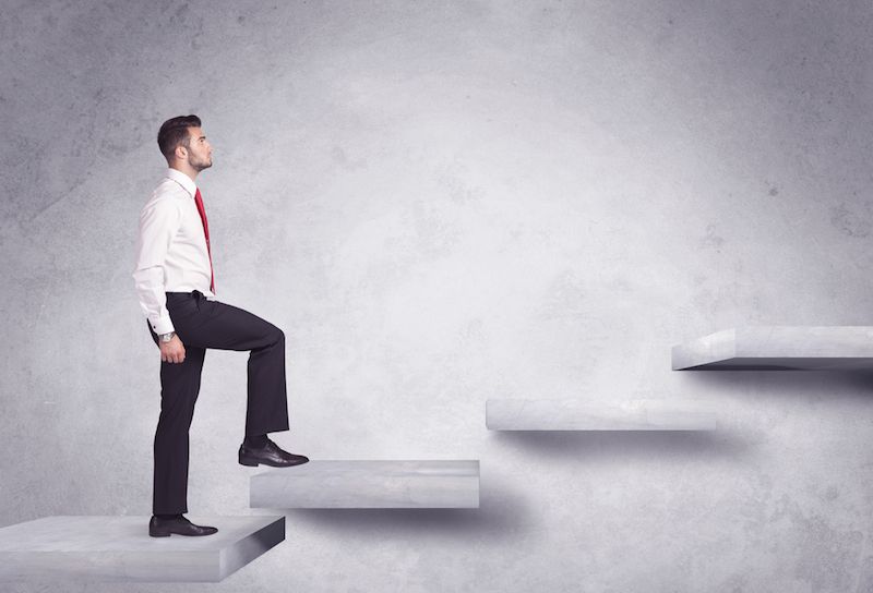 A man in business clothes climbs up a staircase.