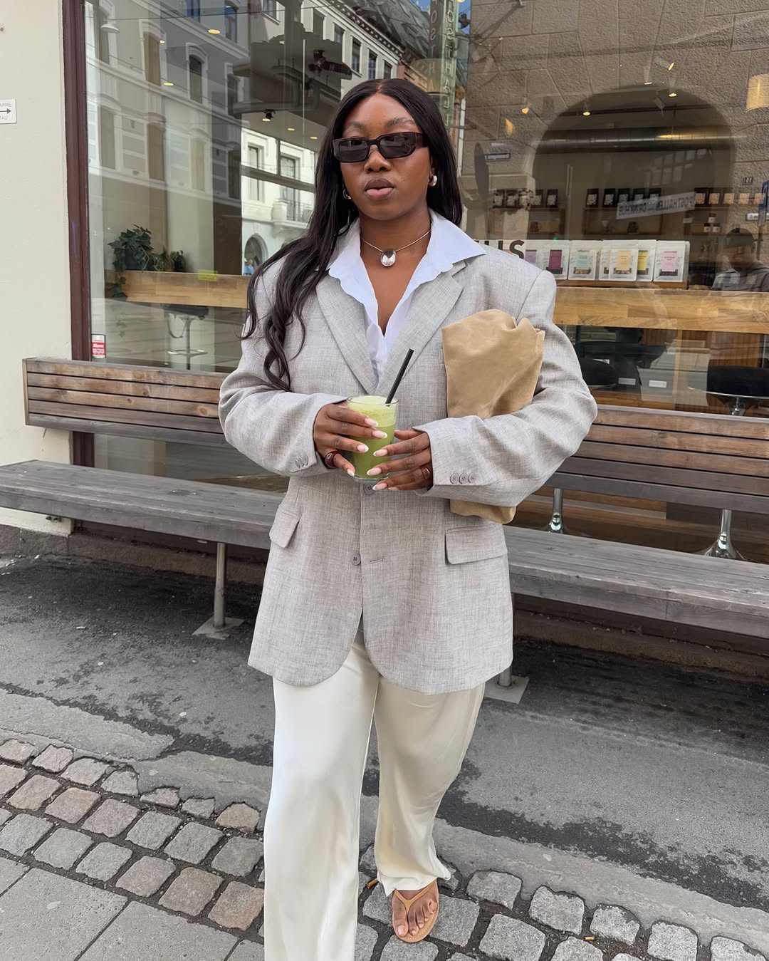 @nnennaechem wears oatmeal suede flip-flops with a light grey linen blazer, cream silk trousers and an oatmeal clutch bag