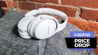White Bose wireless over-ear headphones on a gray pillow with brick wall background